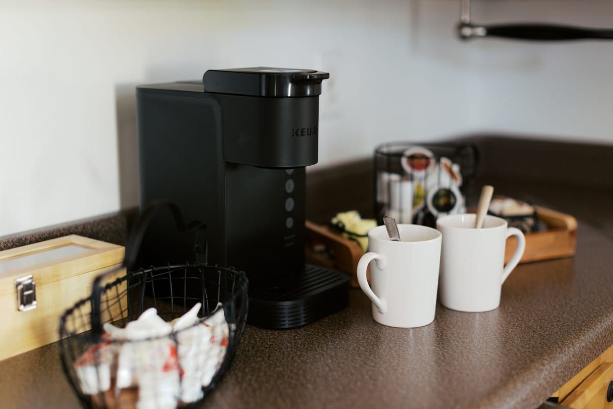 The morning coffee bar with Keurig, mugs, and a basket of pastries