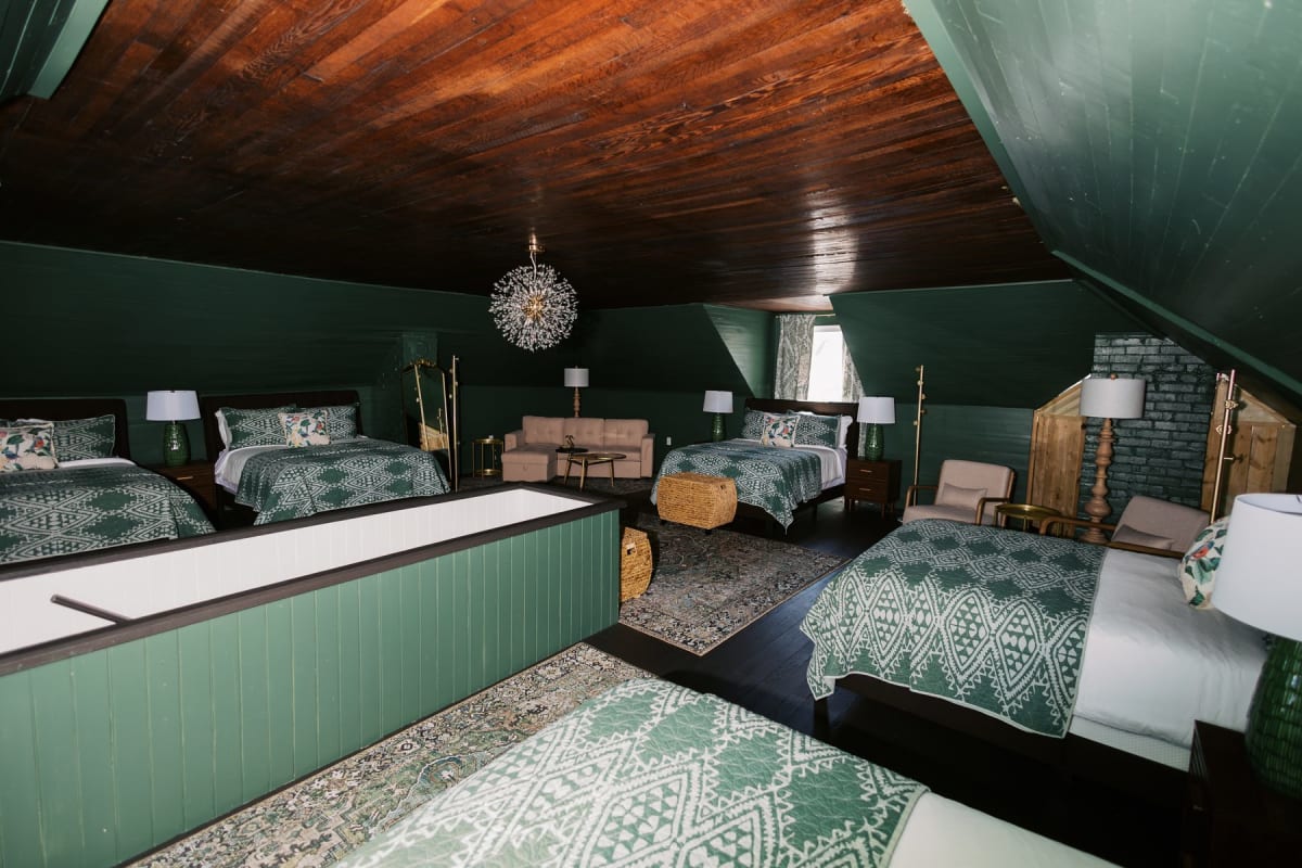 Forest-green attic loft bedroom with exposed pine beams and dormer windows