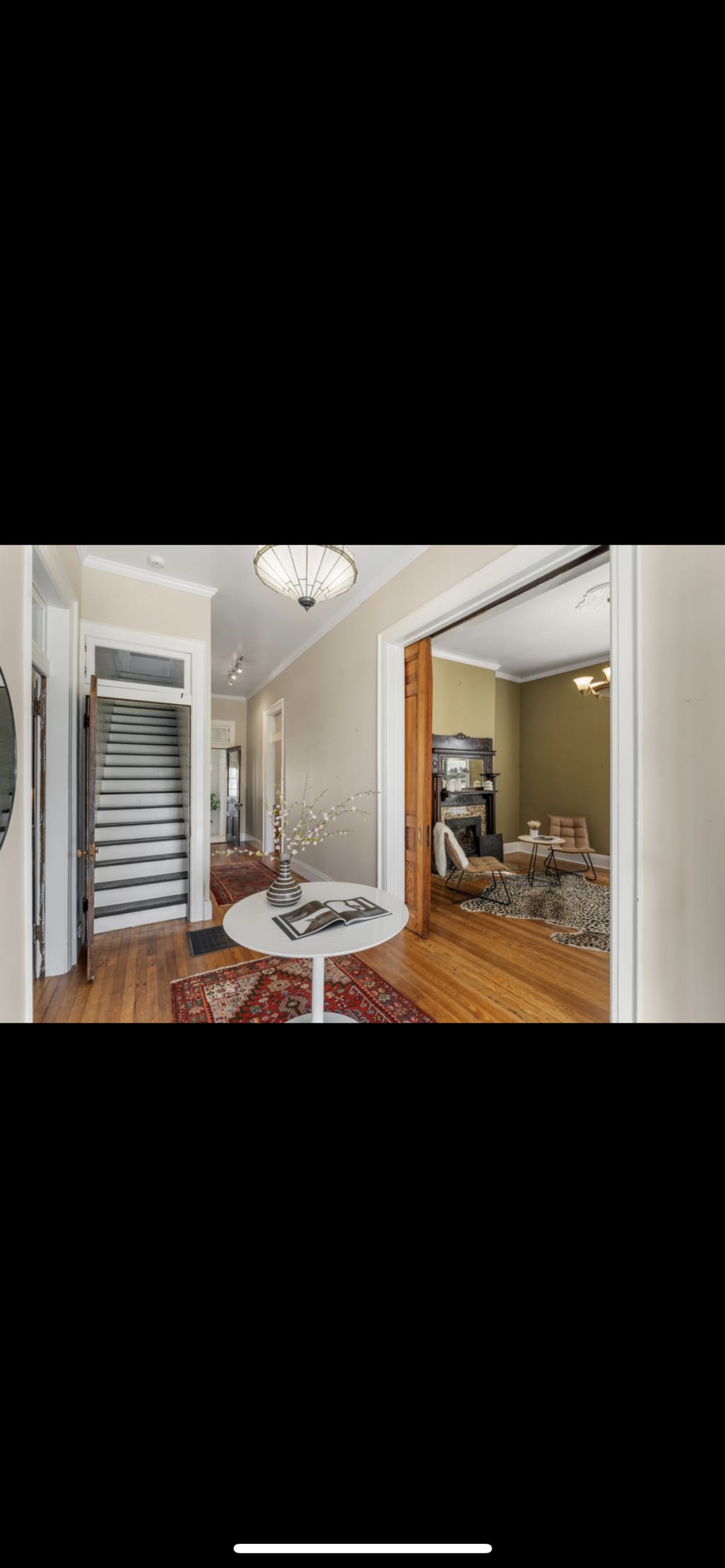 The Entry before restoration — empty hallway with original hardwood floors and staircase