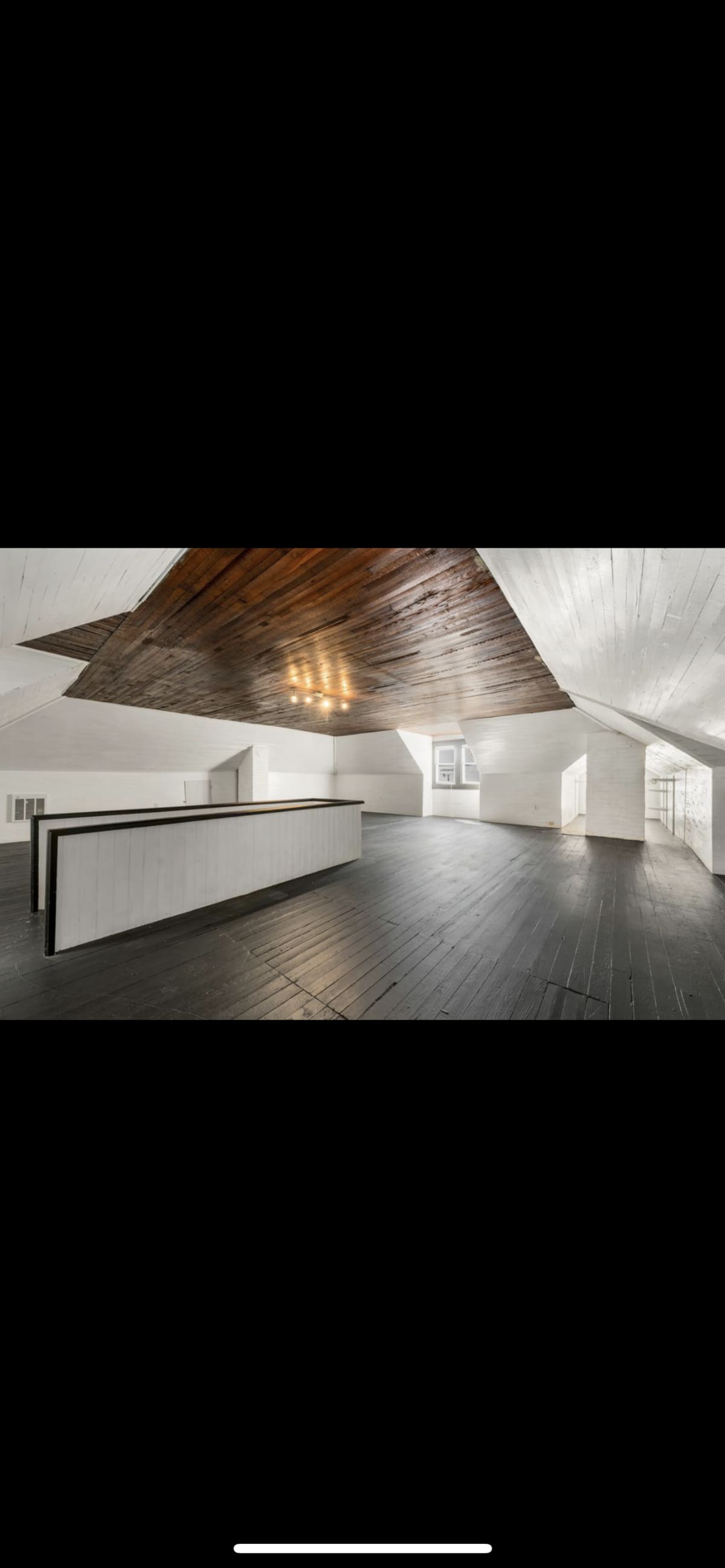 The Loft before restoration — large empty attic with black-stained pine floors and original wood ceiling