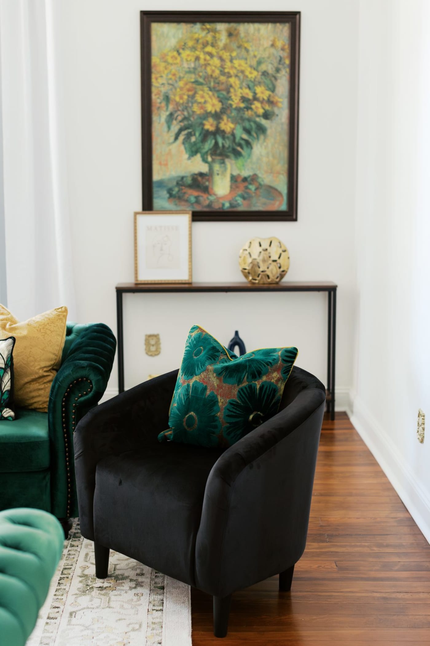 Detail of the emerald velvet chesterfield chair next to brass side table