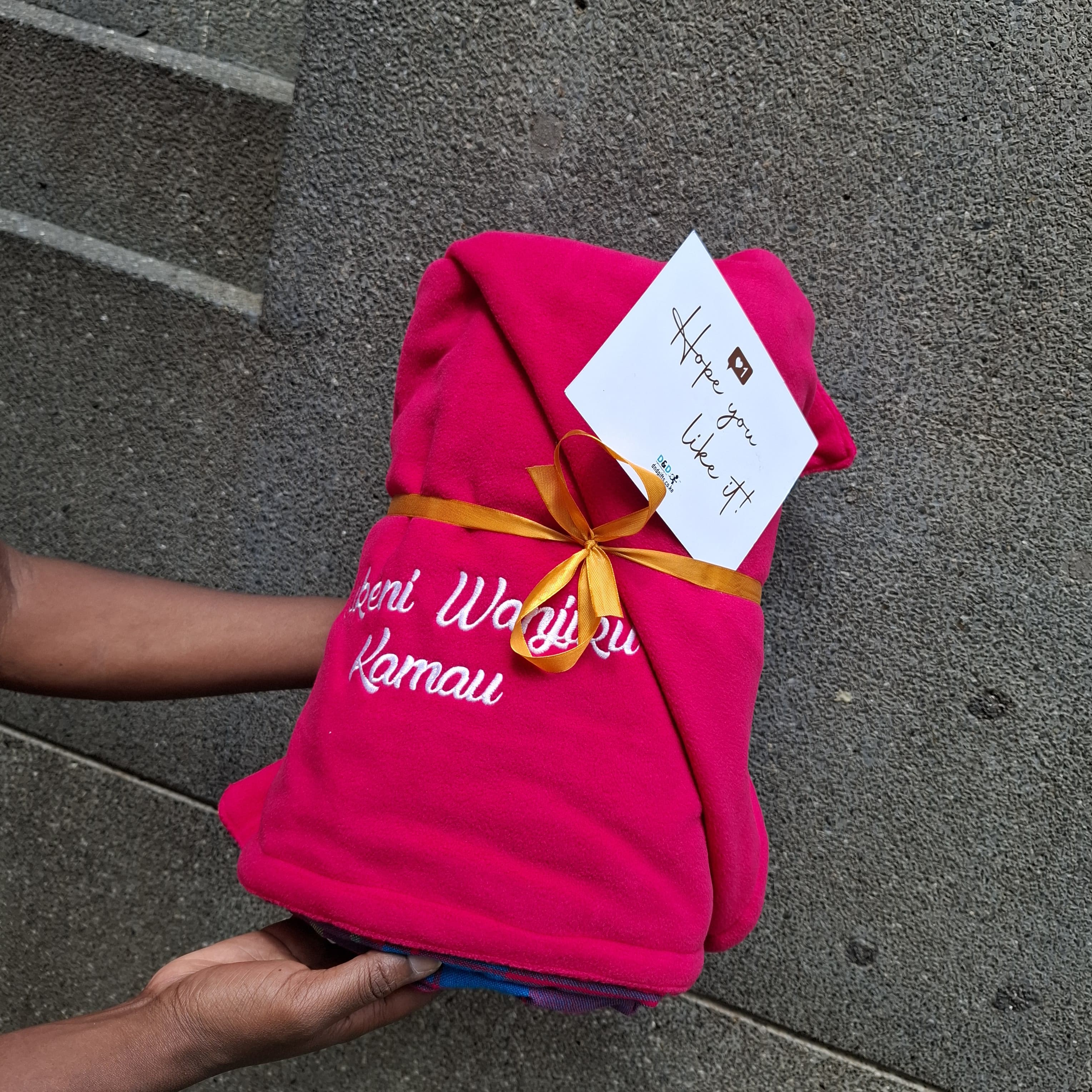 Personalized pink Maasai blanket in Kenya with custom name embroidery