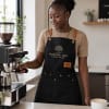 Woman barista wearing custom branded black canvas apron with gold logo print in Nairobi Kenya