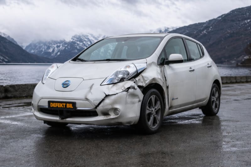 Kollisjonsskadet Nissan Leaf parkert ved fjord — selg din defekte Leaf til Defekt Bil
