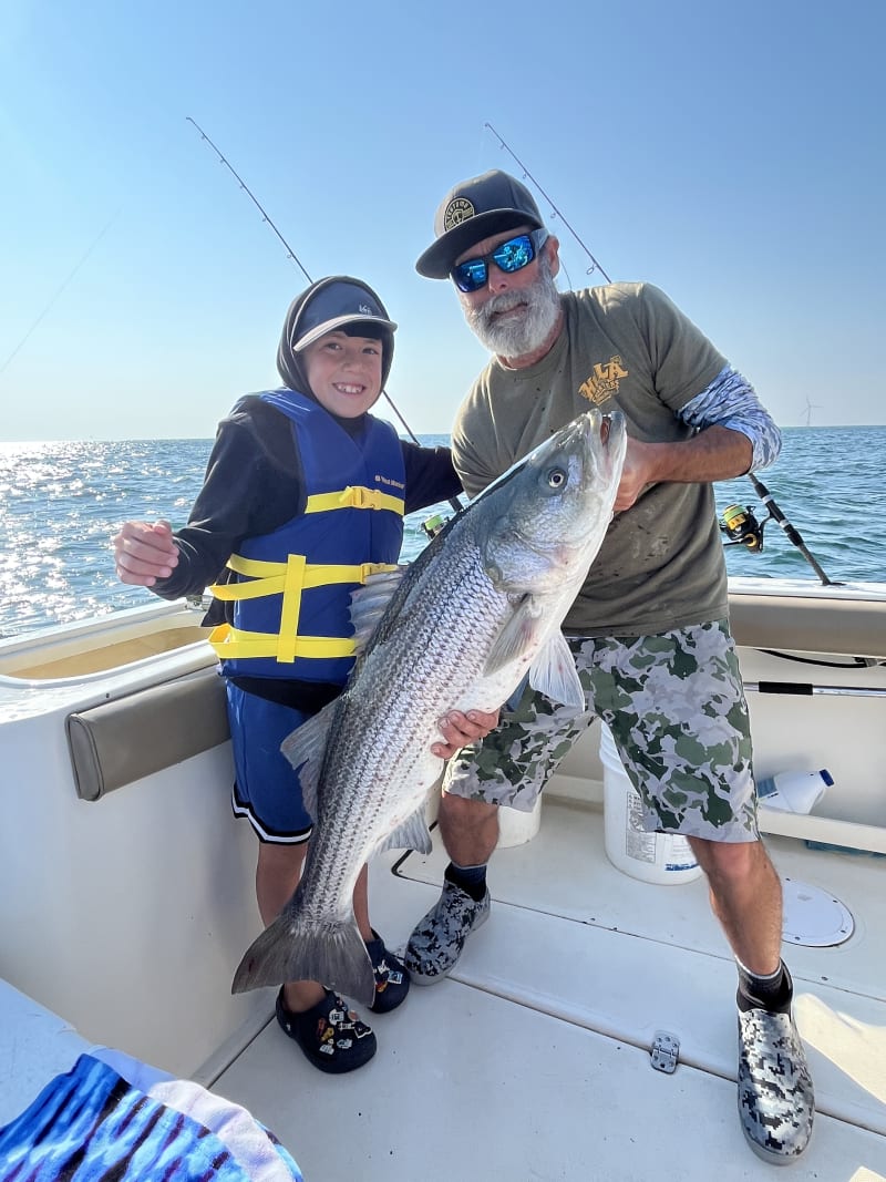A young angler and Captain Matt with a trophy striper caught on light tackle