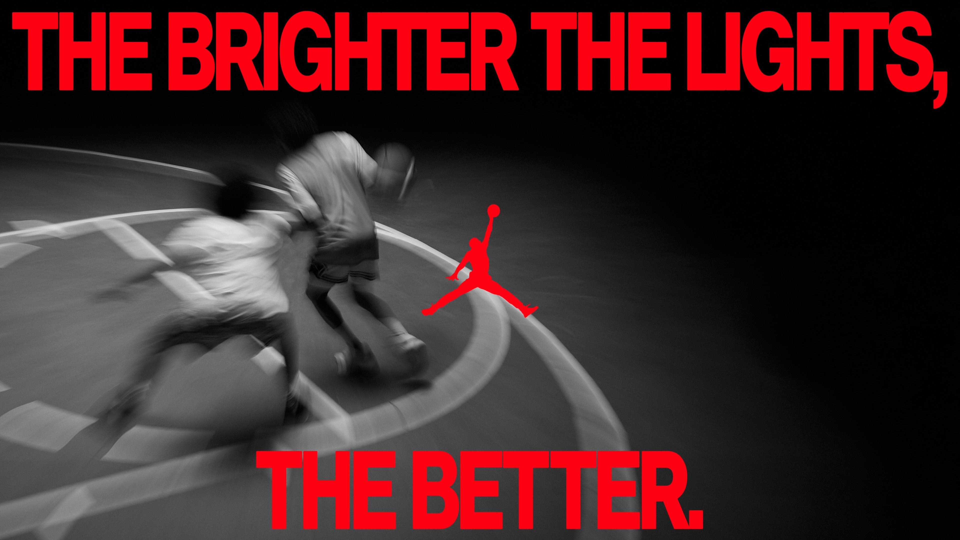 Blurred black and white photo of two basketball players competing on the court. A caption in red font reads, "The brighter the lights, the better." The Air Jordan logo is in the center.