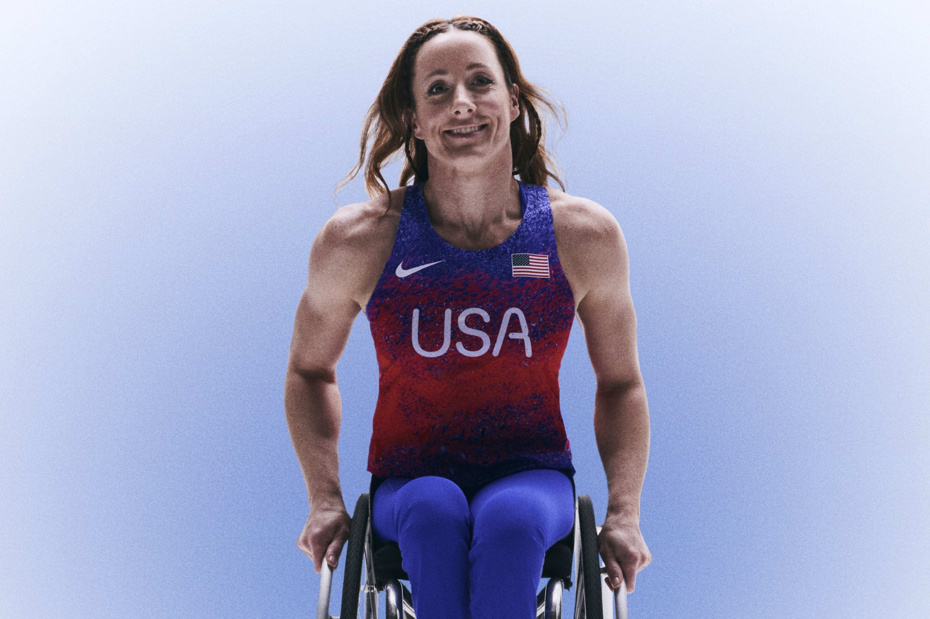 Tatyana McFadden smiling in her wheelchair while wearing her USA track and field kit uniform.