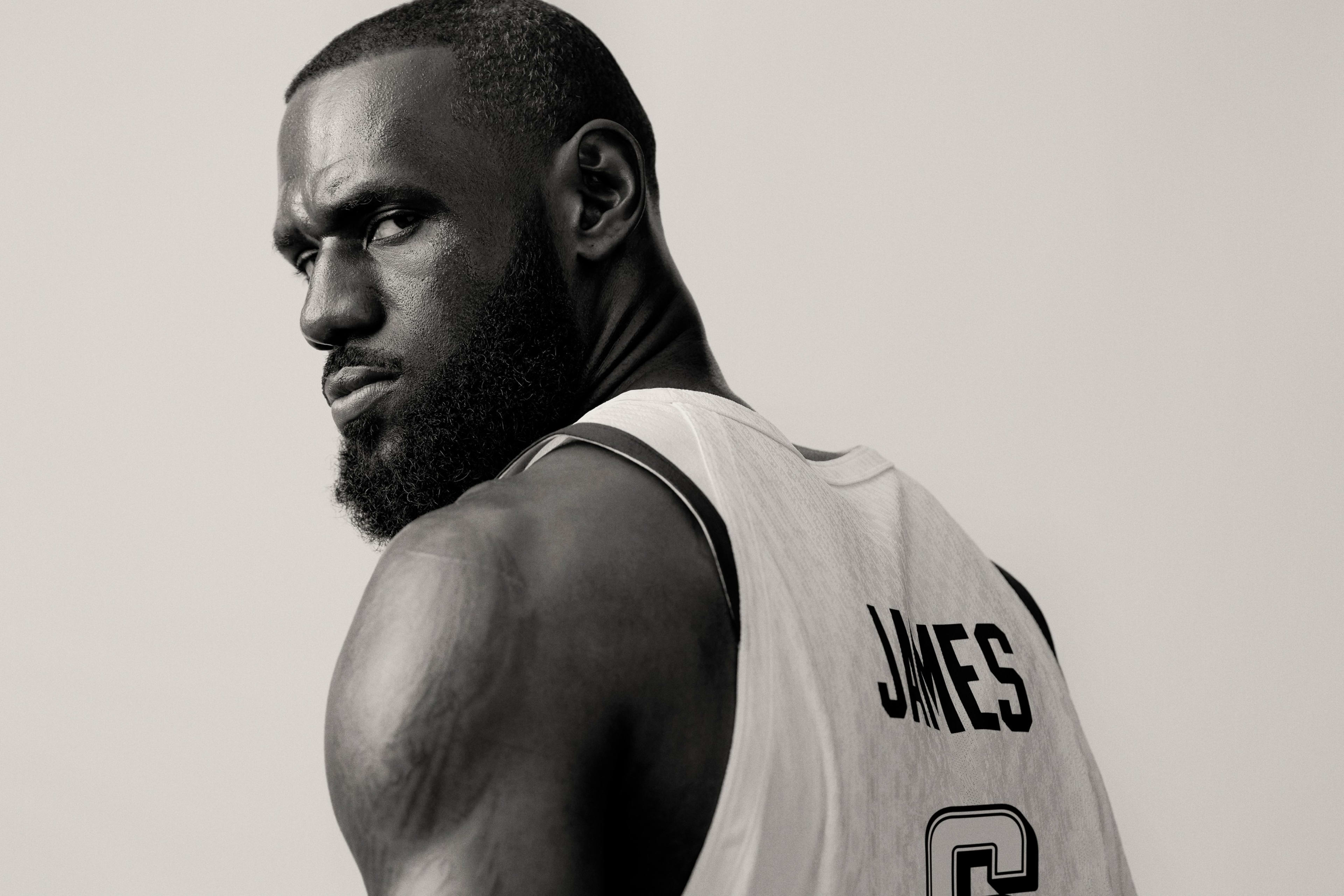 Black and white back angled view of LeBron James solemnly looking back over his shoulder.