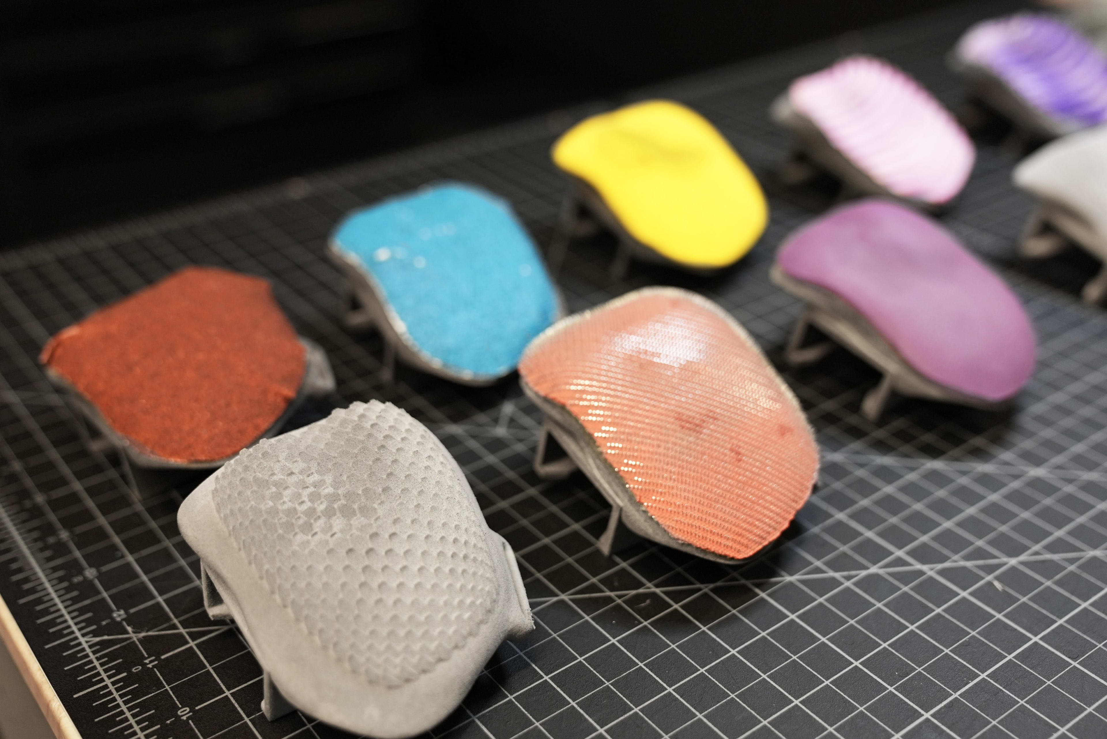 A colorful display of different push glove surface materials sits on a black gridded work surface.