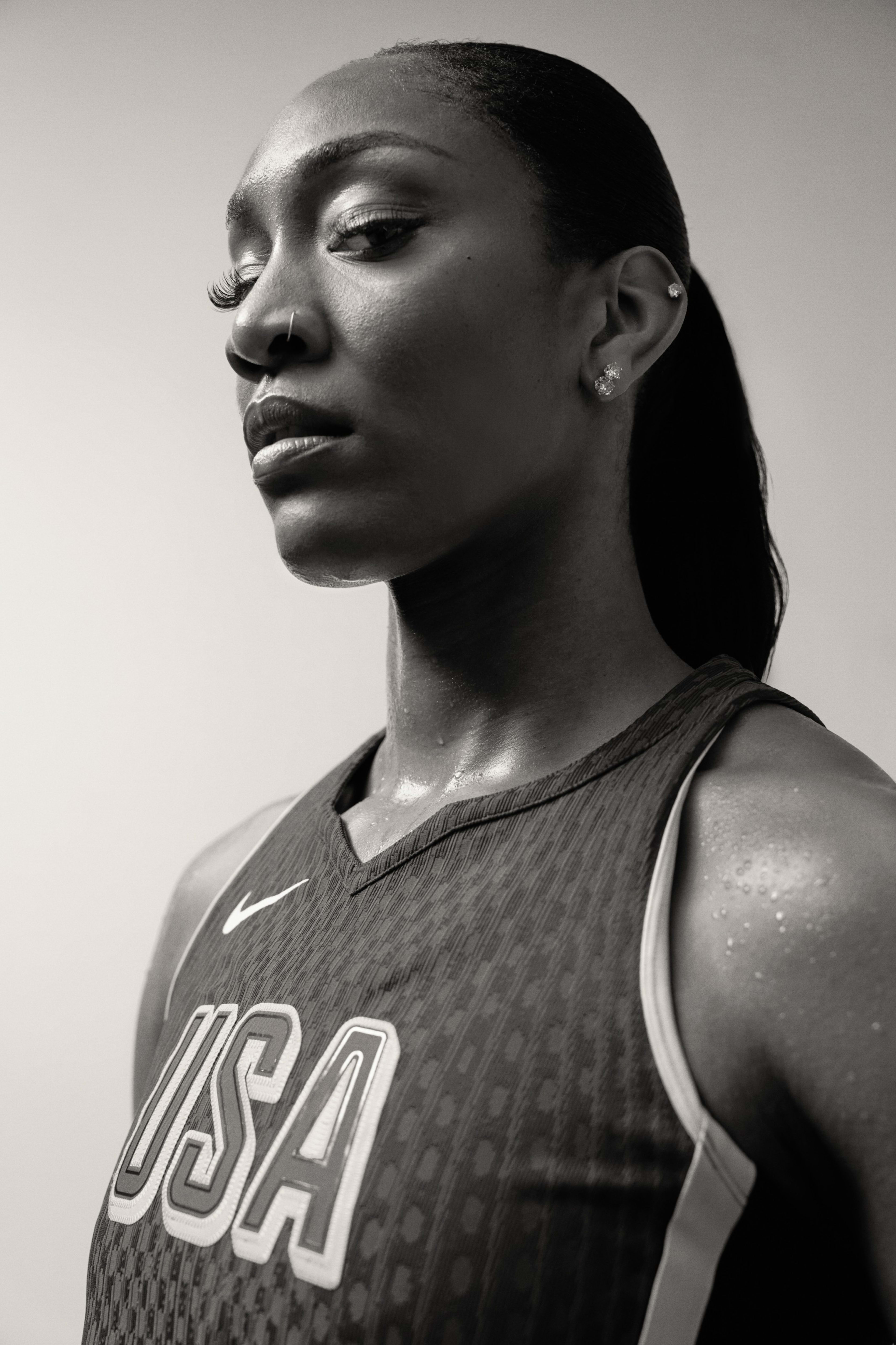 Black and white photo of Aja Wilson wearing her Team USA basketball jersey. She looks down fiercely at the camera.