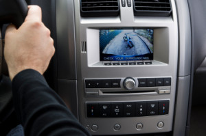 A stock photo of an in dash reversing camera showing the view of a suburban driveway with a child's bike