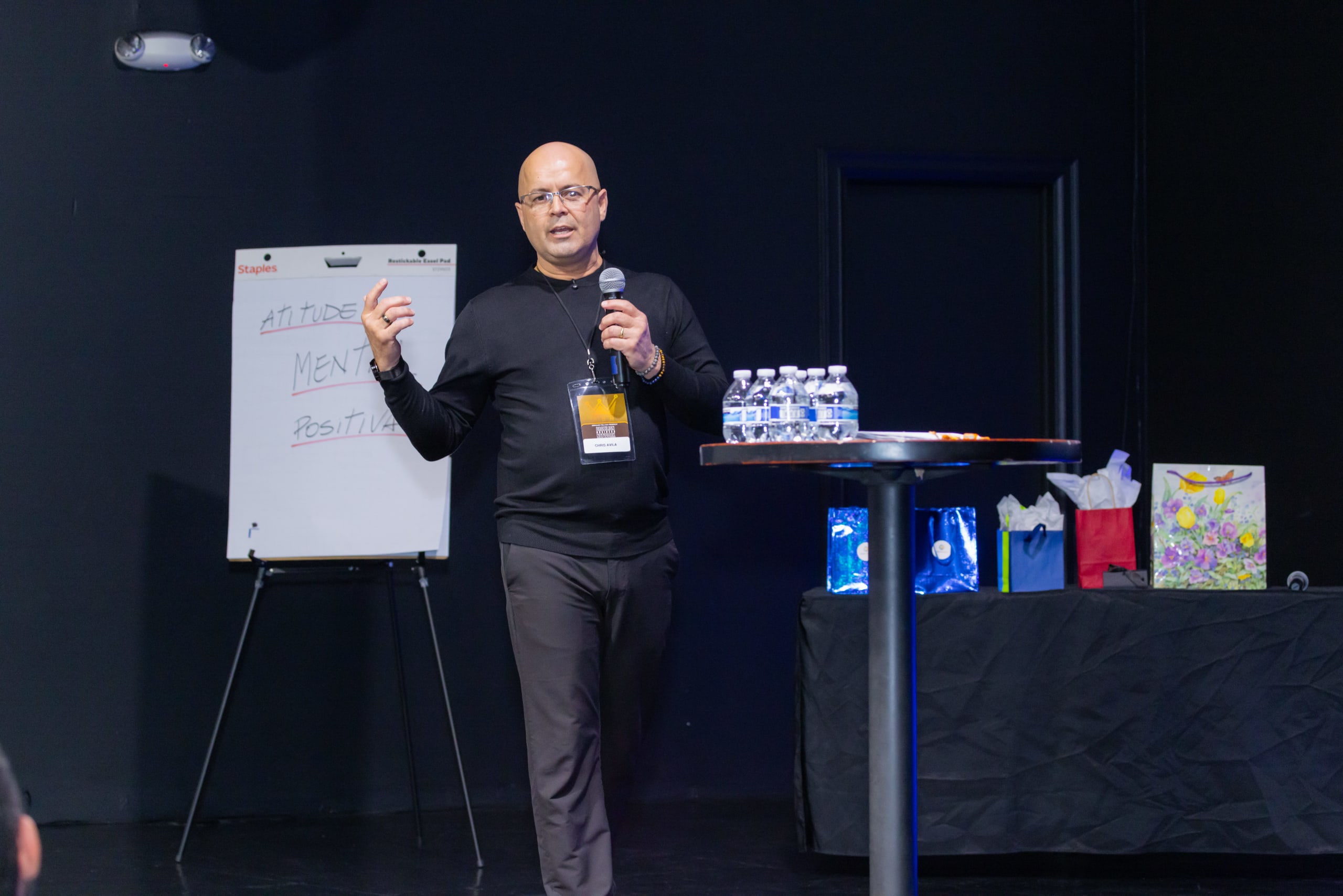 Palestrante apresenta ao lado de um flip chart com a frase “Atitude Mental Positiva”
