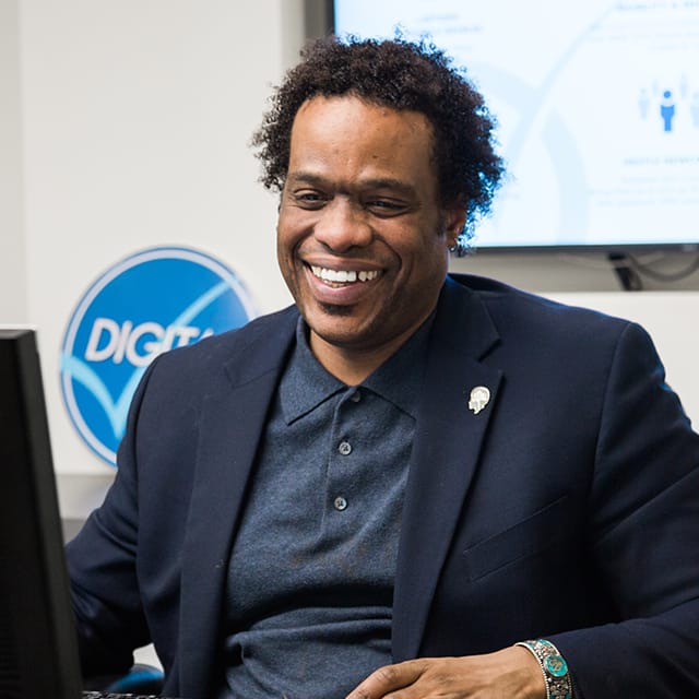 A male nestle tech employee smiling at work, looking at his computer.