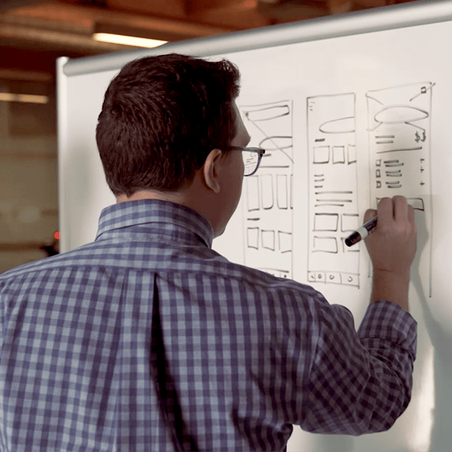 Man writing on a board during an ideation session.