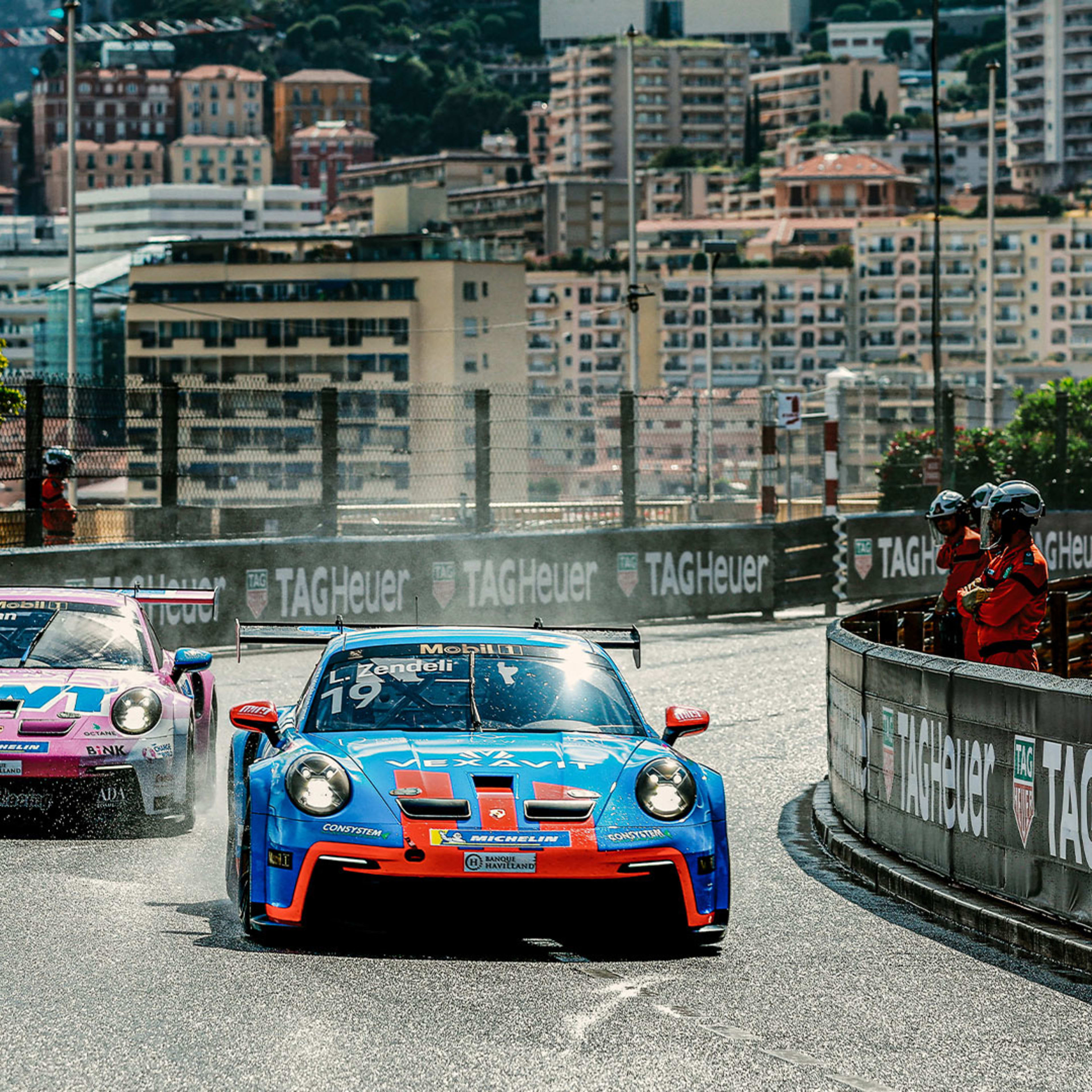 Two Porsche 911 GT3 Cup race cars on a wet track in a corner on the Circuit de Monaco at the 2nd round of the Porsche Supercup 2024