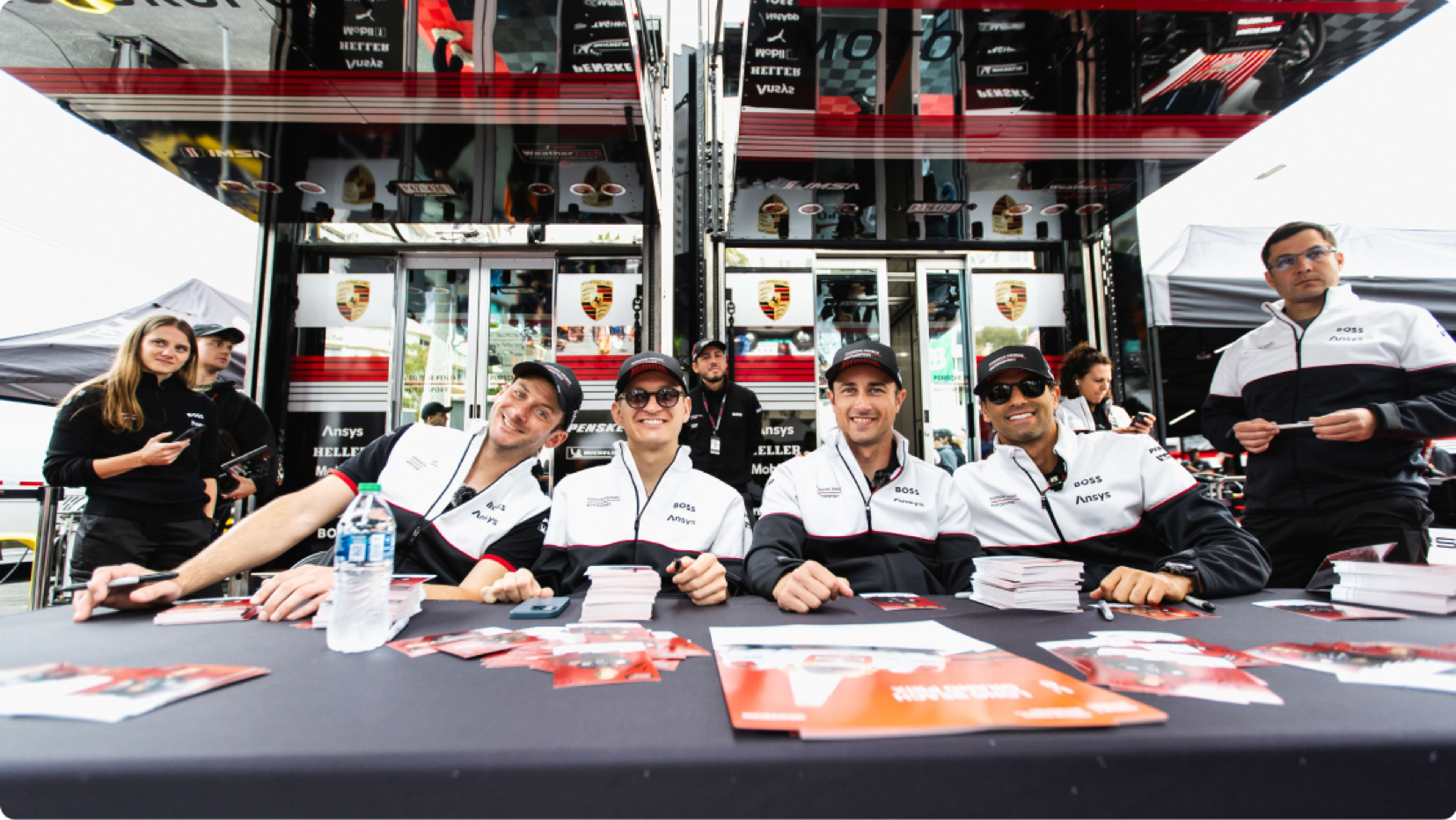 The Porsche Penske Motorsport team sitting at a table together at a fan meeting session