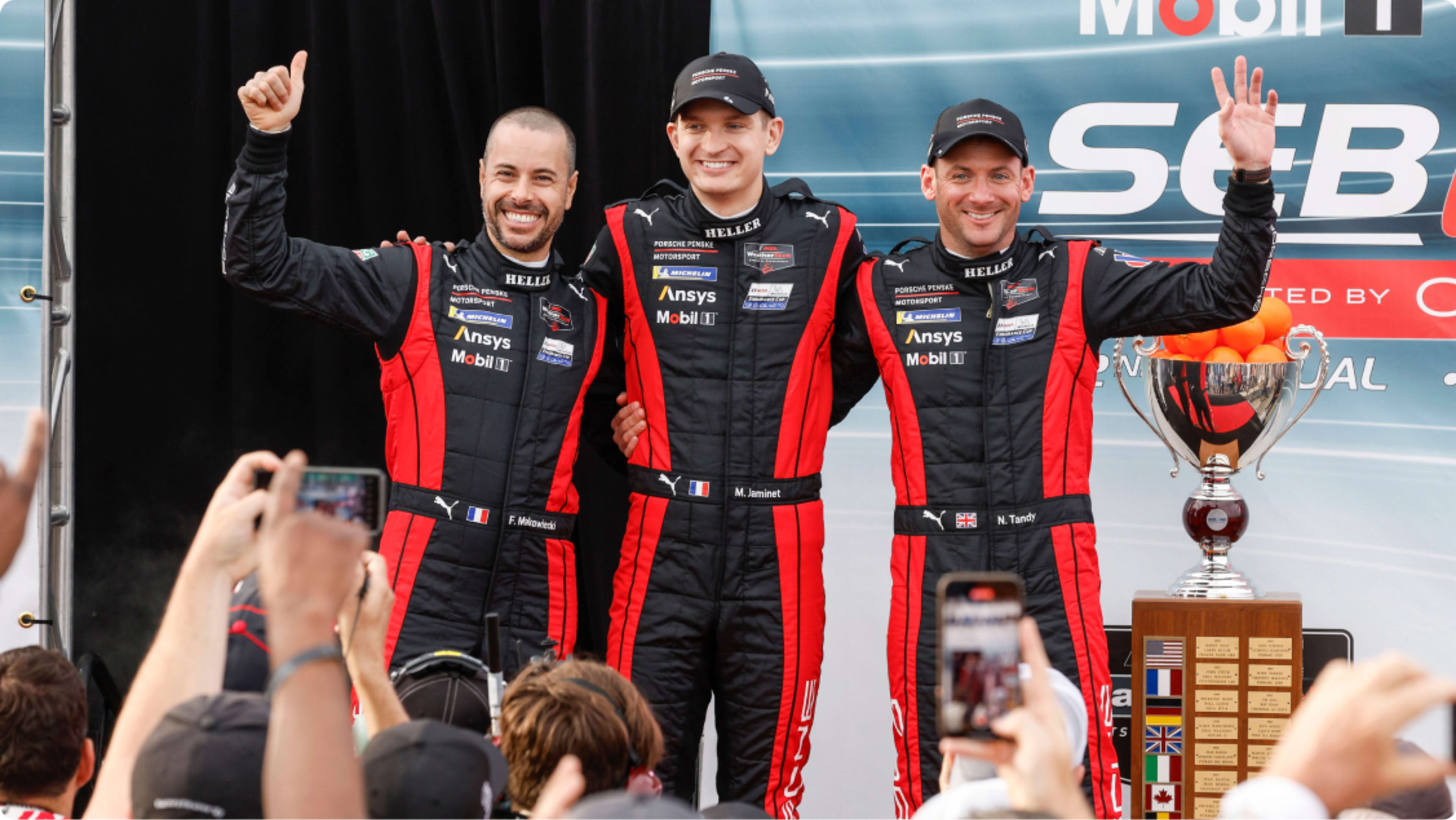 Three drivers cheering in front of crowd