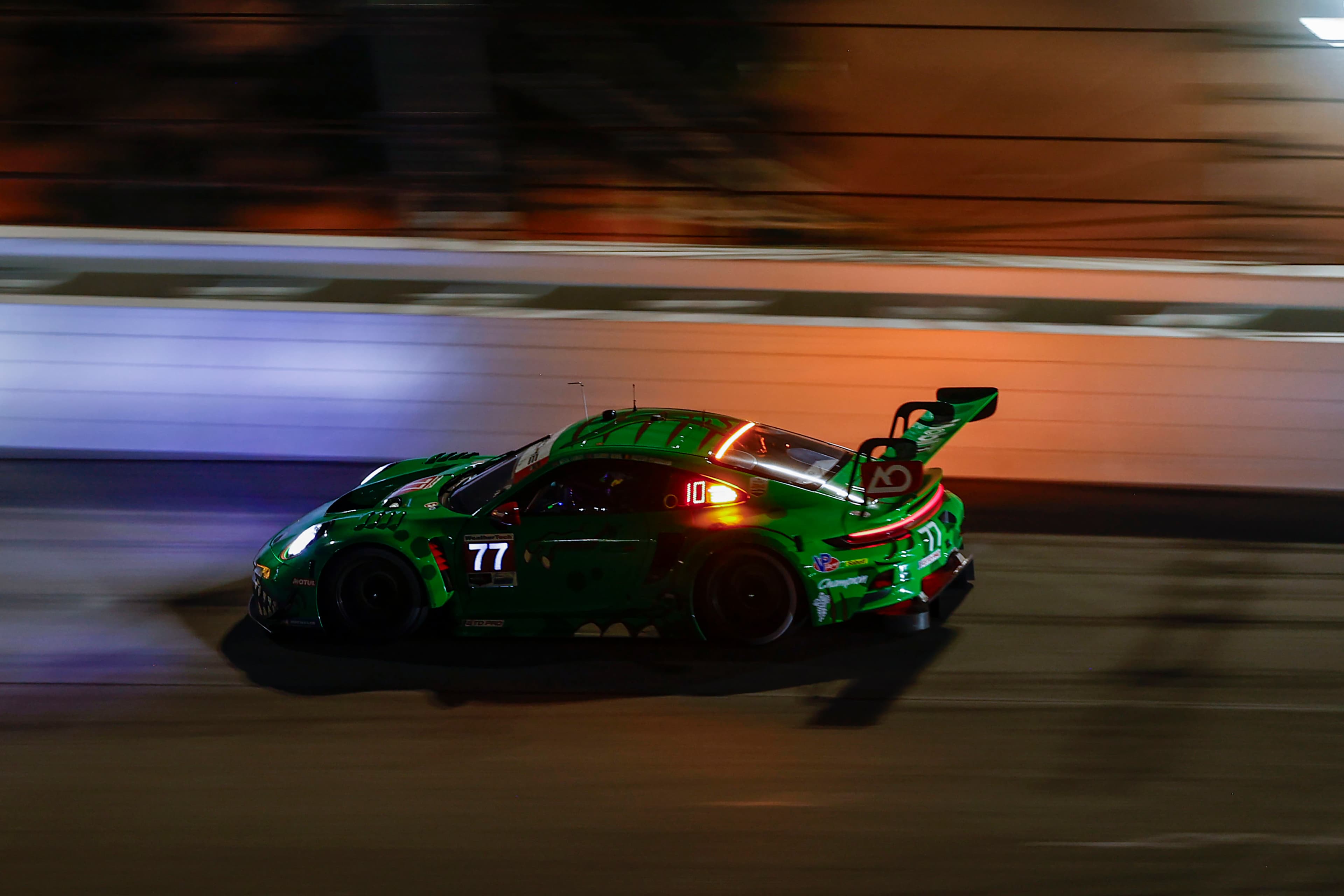 The #77 AO Racing car turns a corner during the night
