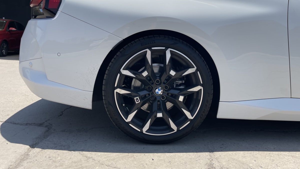 2025 BMW M220 - Detalle lateral trasero de hatchback blanco. Rueda con llanta bitono en exterior.