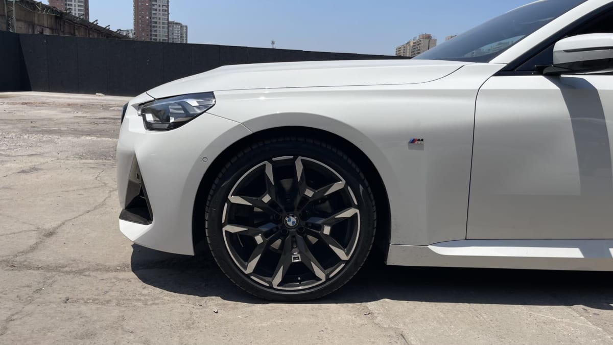 2025 BMW M220 - Vista 3/4 frontal de hatchback color blanco en exterior. Detalle de neumático.