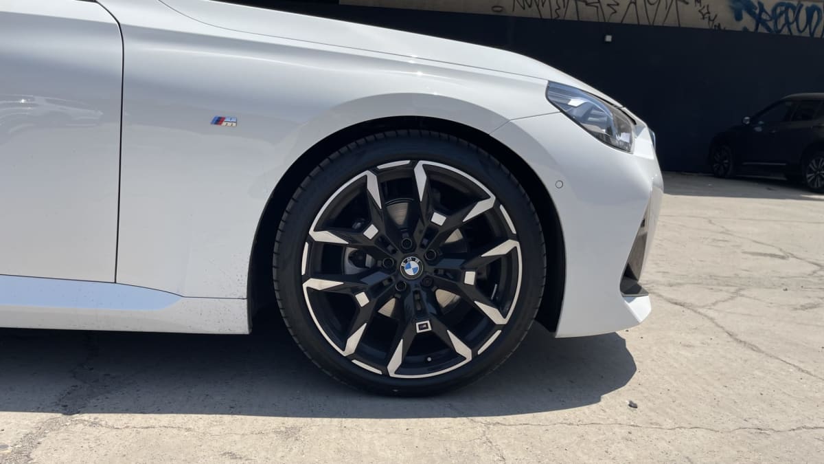 2025 BMW M220 - Detalle 3/4 de hatchback color blanco. Exterior, con foco en neumático y parte frontal.