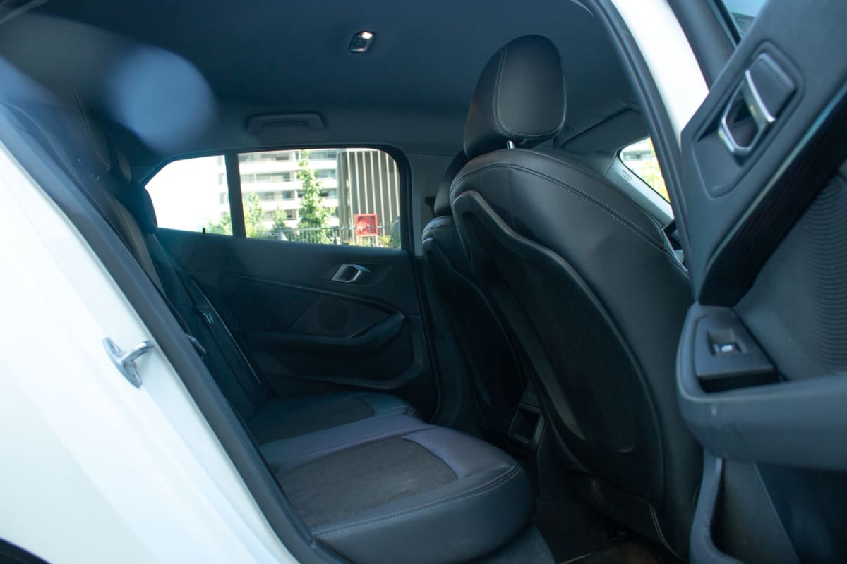 BMW 118d 2.0 2021 - Interior de hatchback blanco. Vista de asientos traseros de cuero negro. Exterior.