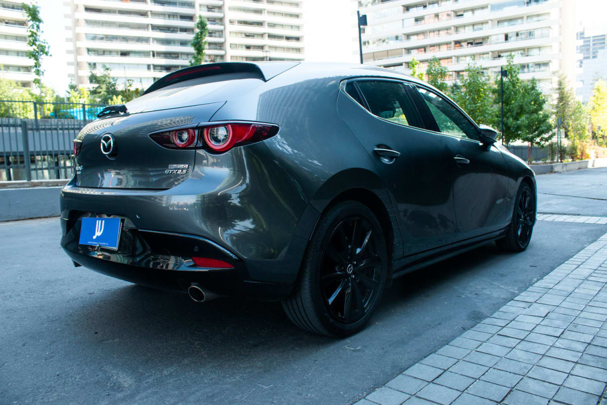 Mazda 3 2.5 2024 - Vista trasera 3/4 de hatchback color gris oscuro en exterior