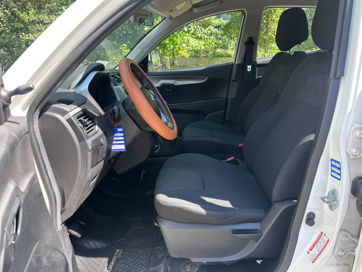 Mahindra XUV100 2021 - Vista interior de pickup color blanco, asientos negros, en exterior.