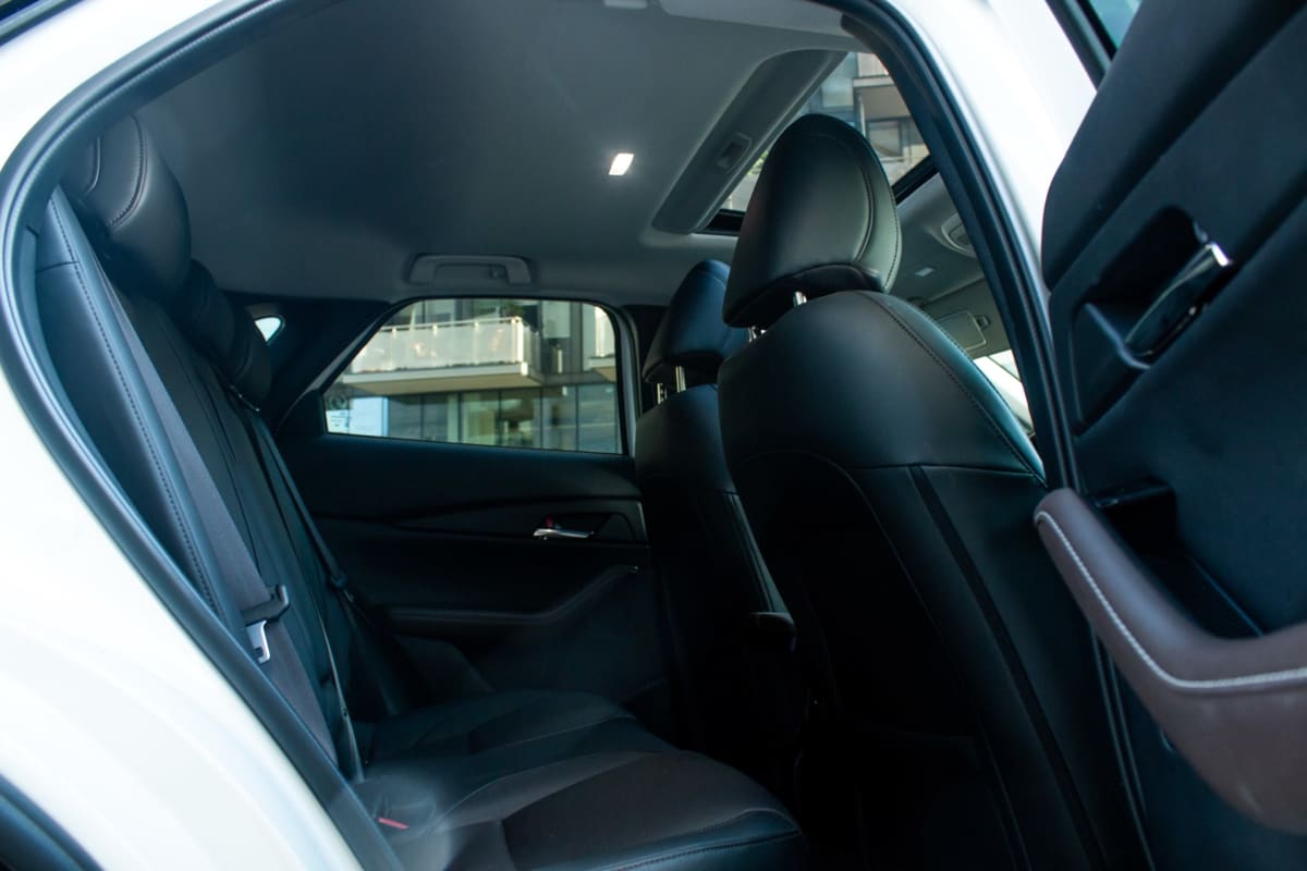 Mazda CX-30 High 2024 - Interior de hatchback blanco. Vista de asientos traseros de cuero negro y sunroof.