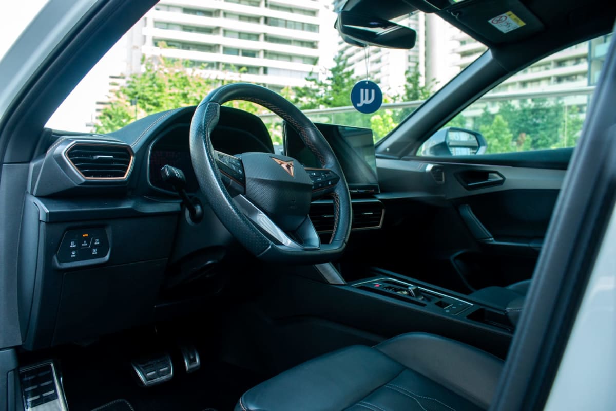 Cupra Formentor VZ 2023 - Vista interior delantera, color blanco, tipo hatchback en exterior. Volante y tablero en primer plano.