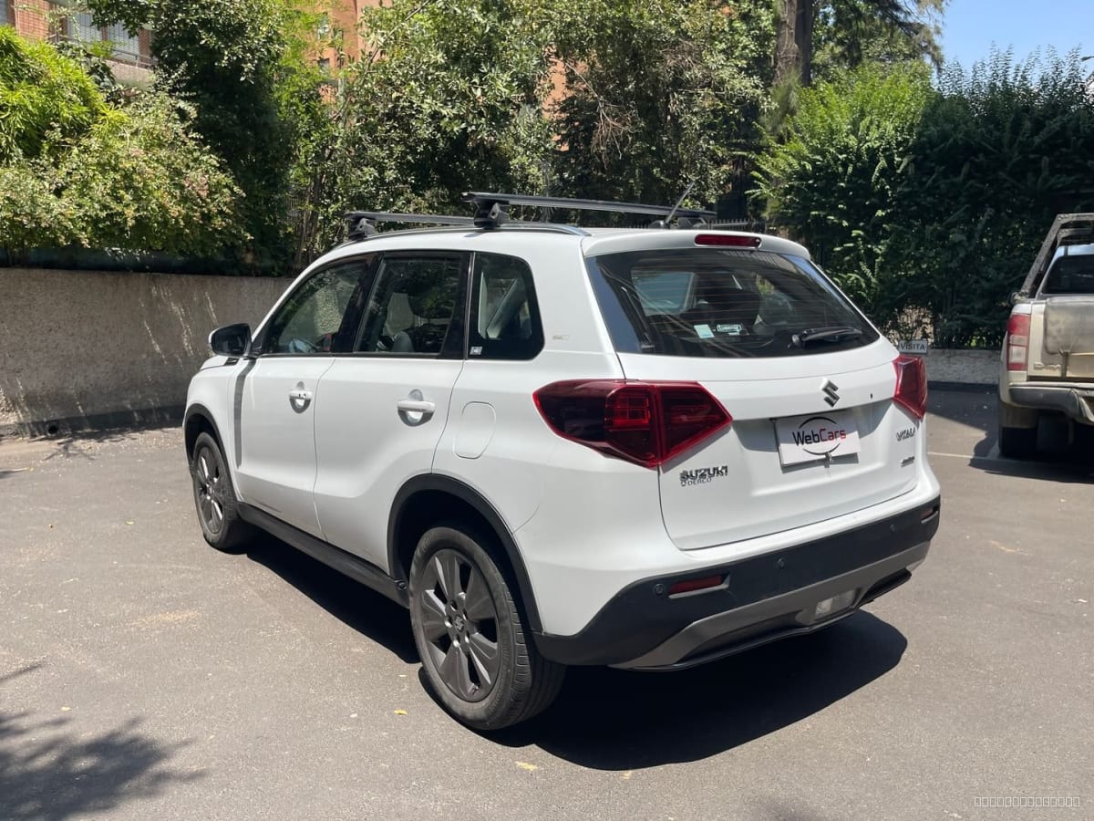 Suzuki Vitara 1.6 GLX 4x4 2022 manual - Vista trasera 3/4 de SUV color blanco en exterior con barras portaequipaje