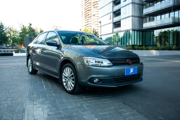 Volkswagen Vento 2.0 2013 - Vista 3/4 de sedán color gris en exterior. Edificio moderno de fondo.