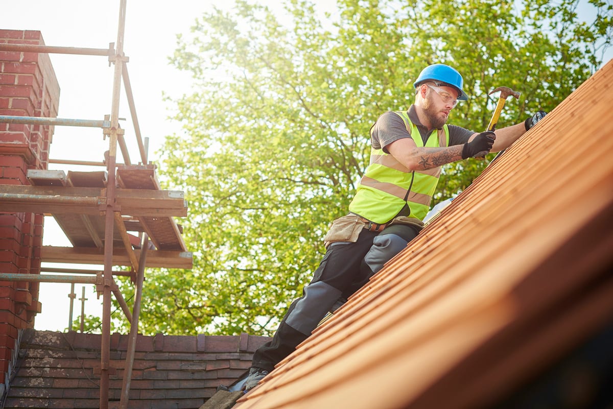 Am Norfolk Roofing Services roofer hammering tiles into roof battons