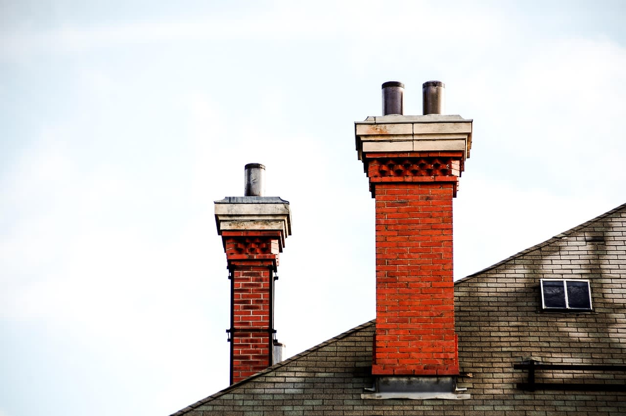 Schornsteinfeger arbeitet auf einem Hausdach am Schornstein