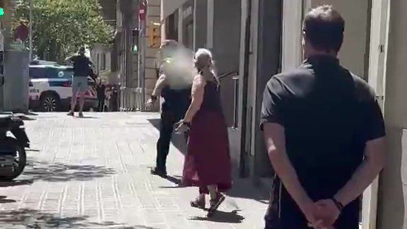 Una mujer utiliza spray pimienta contra un agente durante una operación policial por un hombre armado con un machete en Barcelona