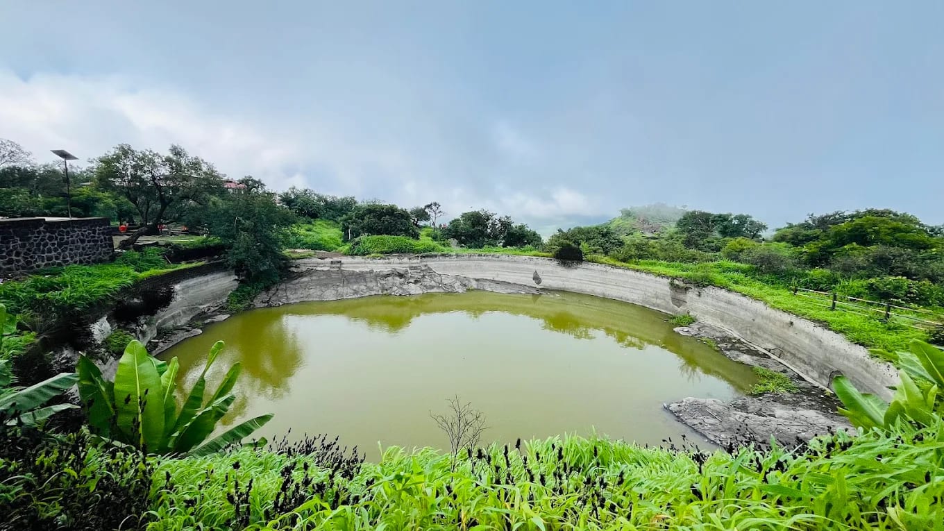 Natural rock-cut water cistern (Dev-Taaki) at Sinhagad Fort filled with crystal-clear mountain water