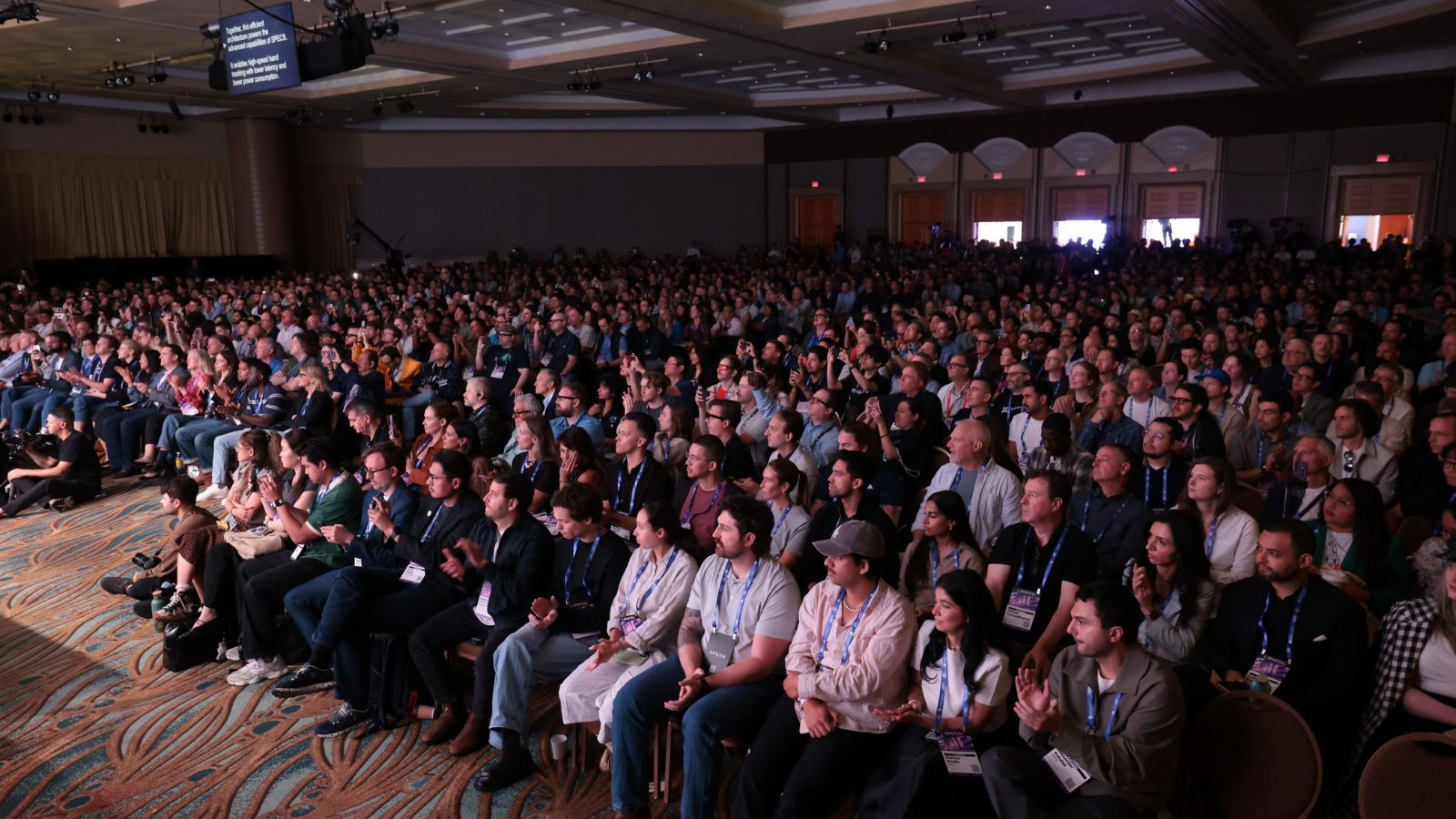 A packed conference audience at a keynote session