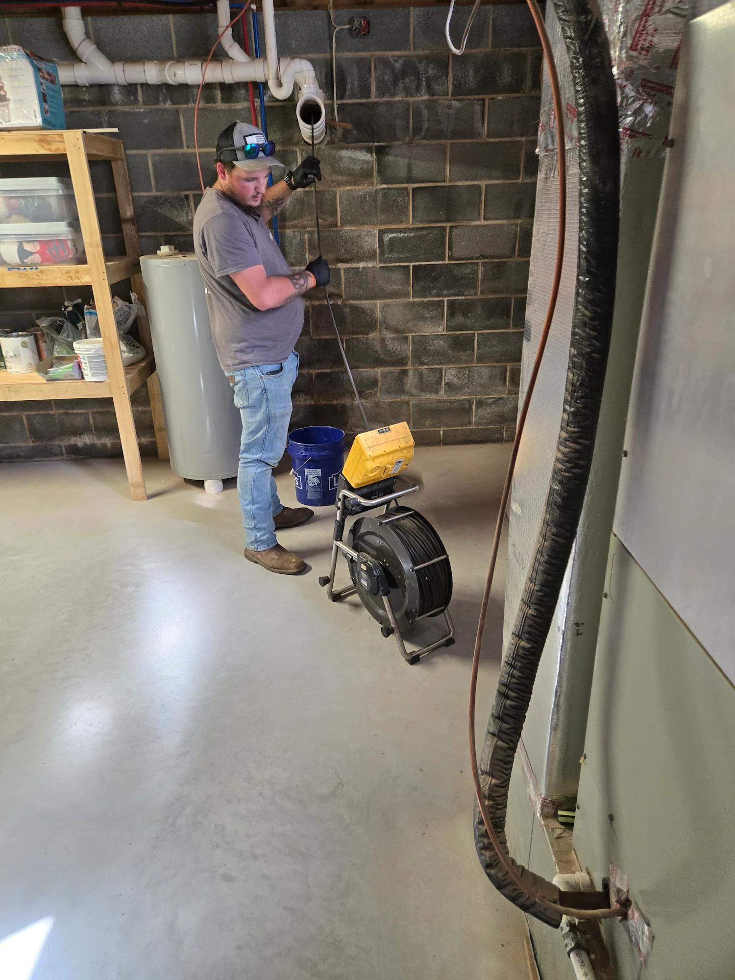 Carlisle technician feeding a SeeSnake camera into a basement cleanout with the monitor beside him