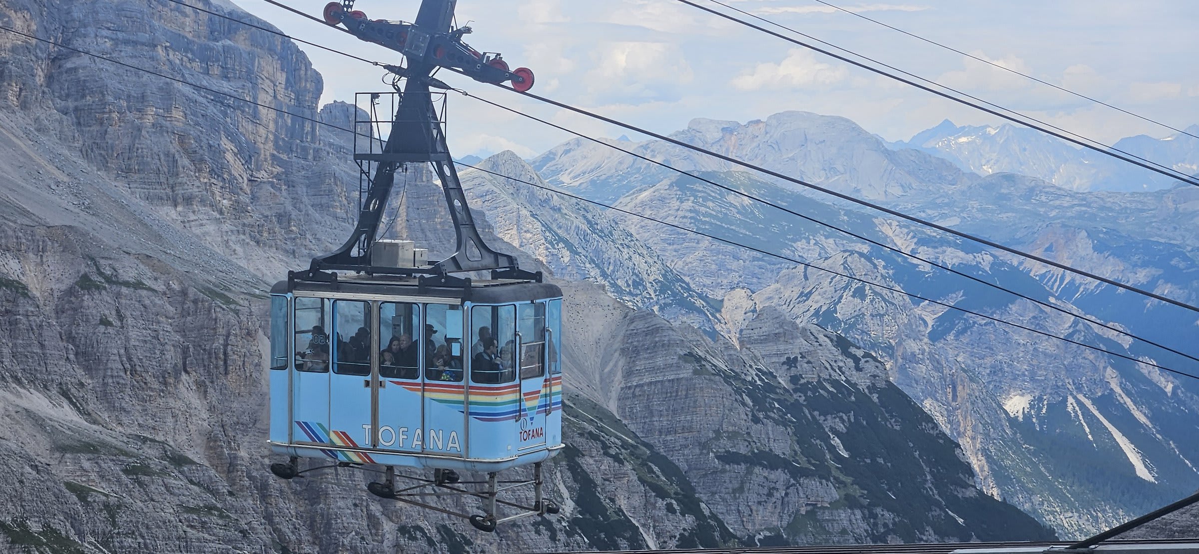 Cable car gondola ascending the mountainside with dramatic Dolomite scenery