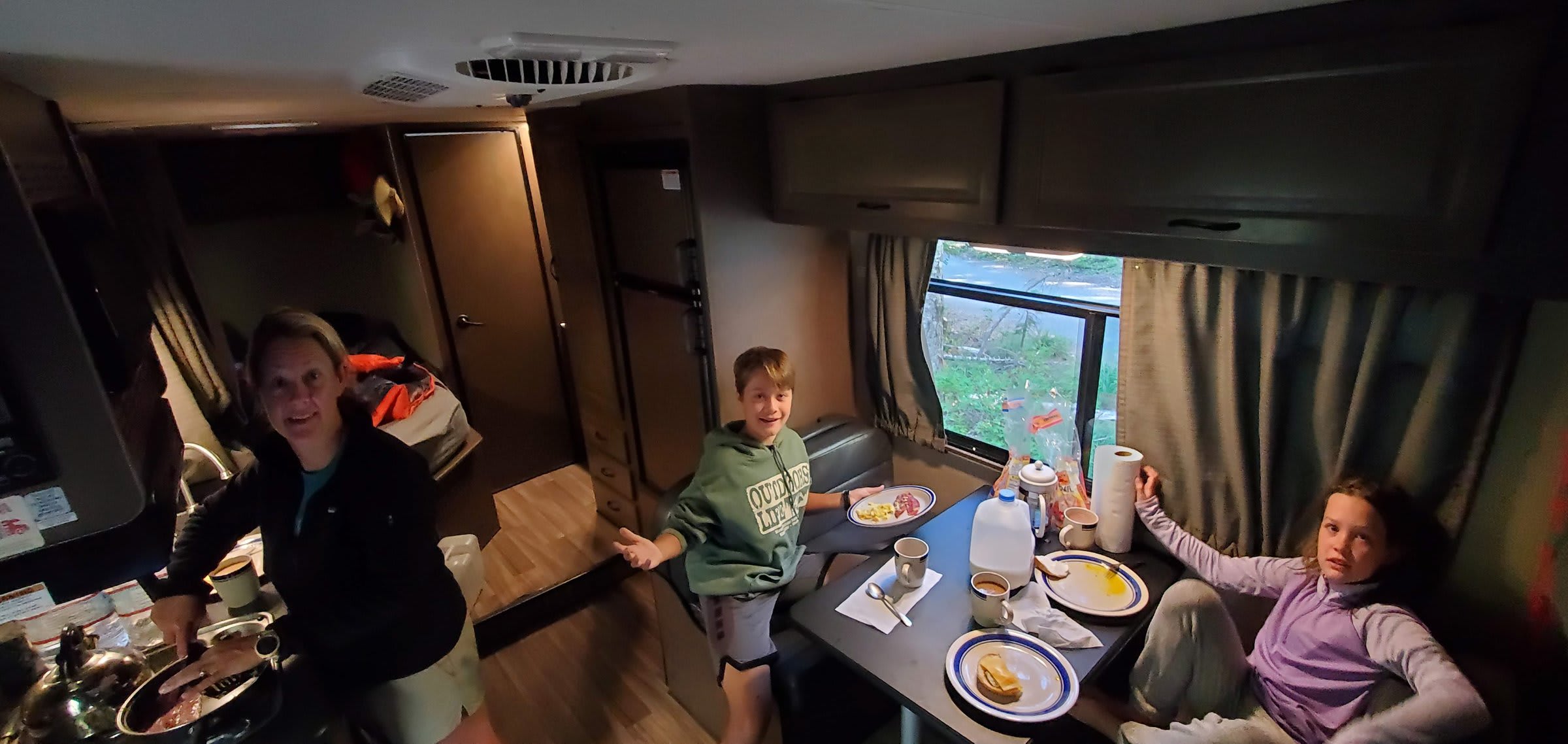 Family breakfast inside an RV — cooking on the stove while the kids eat at the dinette