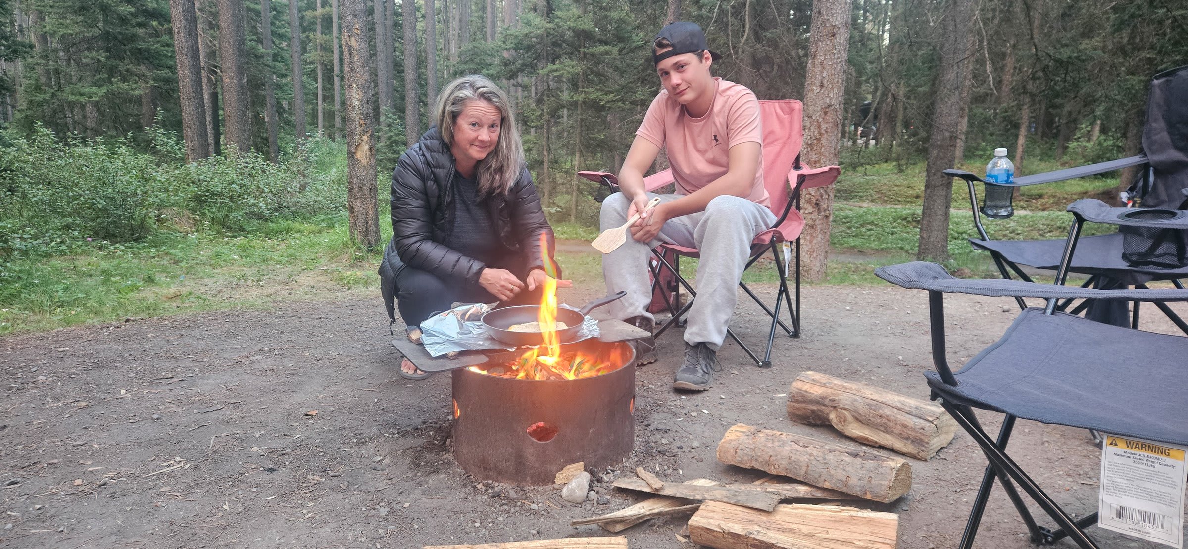 Cooking in a skillet over a metal fire ring at a forest campsite