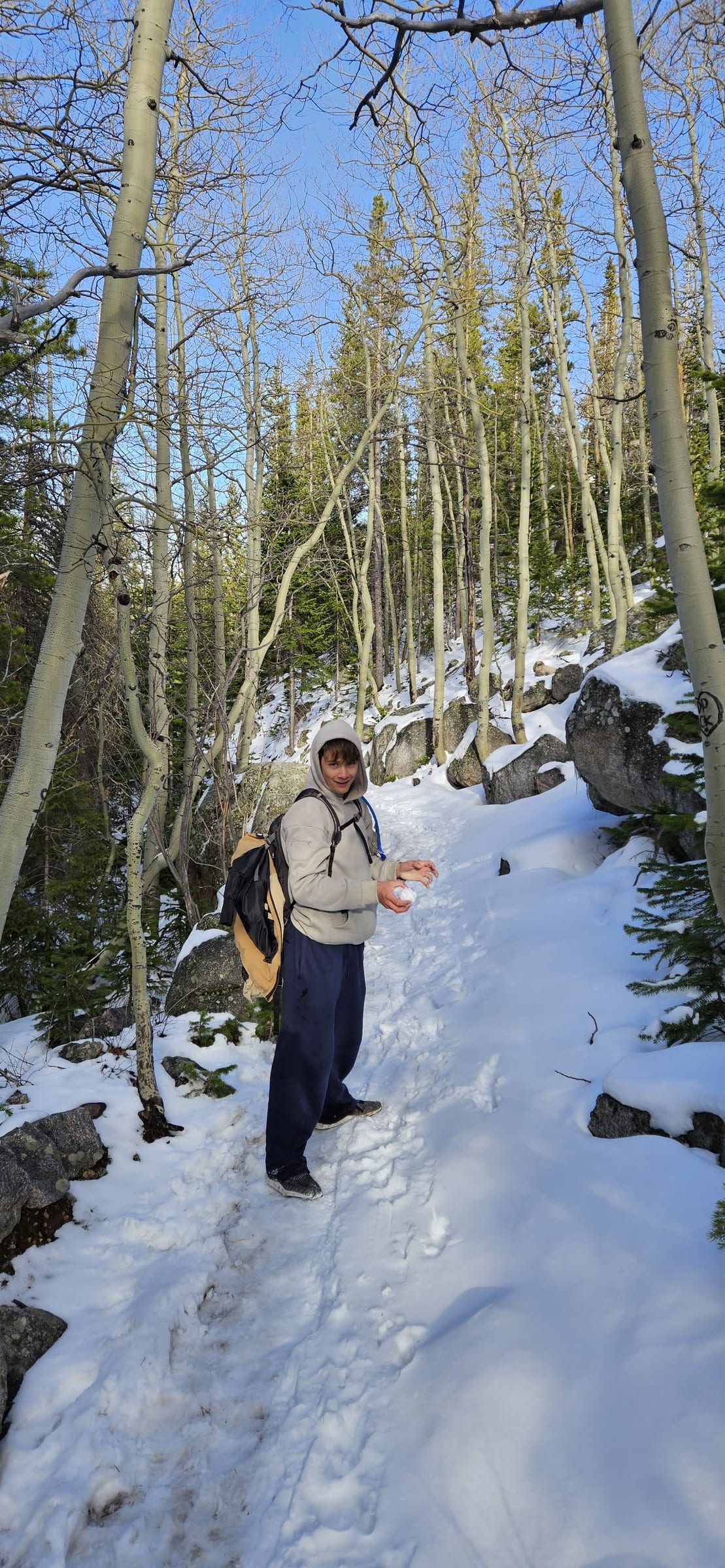 Family hiking through deep snow on the creekside trail