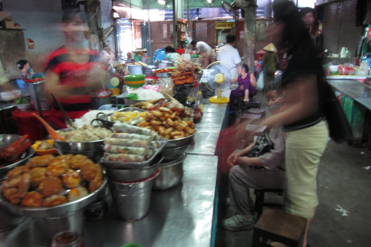 Inside what was an airplane hangar, is now a market. Table of food and goods for sale.