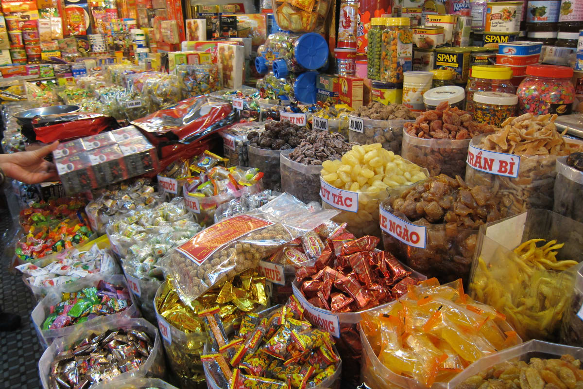 Market goods on display. Colourful bags and containers of all types of sweets or savoury snacks, mixtures of seaonsings and spices, coffee, and more.