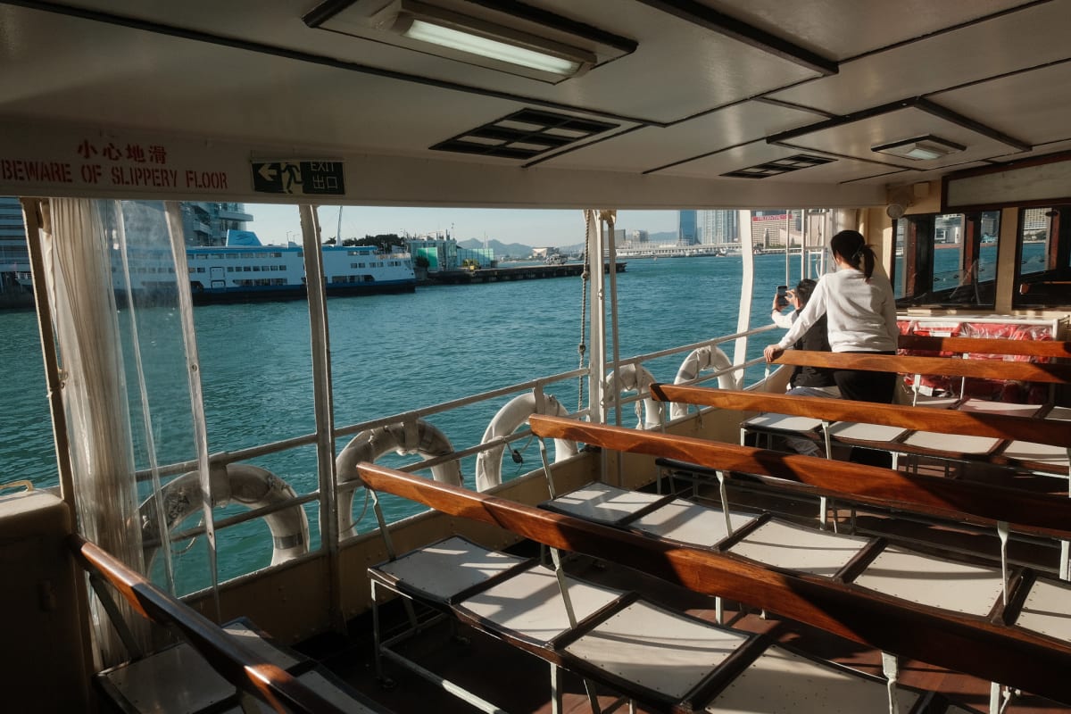 Two people look out from inside the Star Ferry at a ship docked at the Hong Kong convention centre.