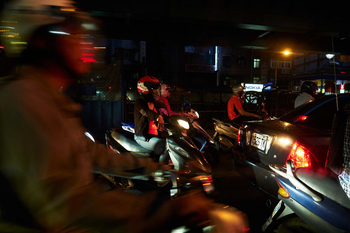 Scooters line up around cars.