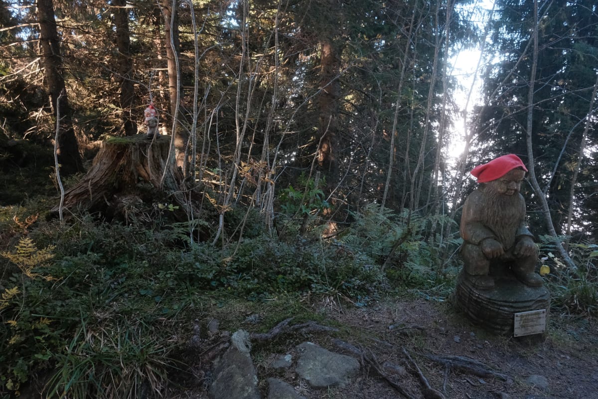 Two more gnomes guard the entrance to the cave, one using a red cloth as a hat.