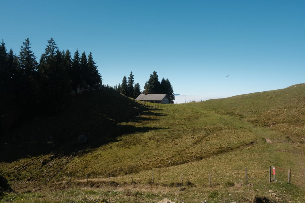 A farmer's hut along the way, with stark boulders on a hill beside it.