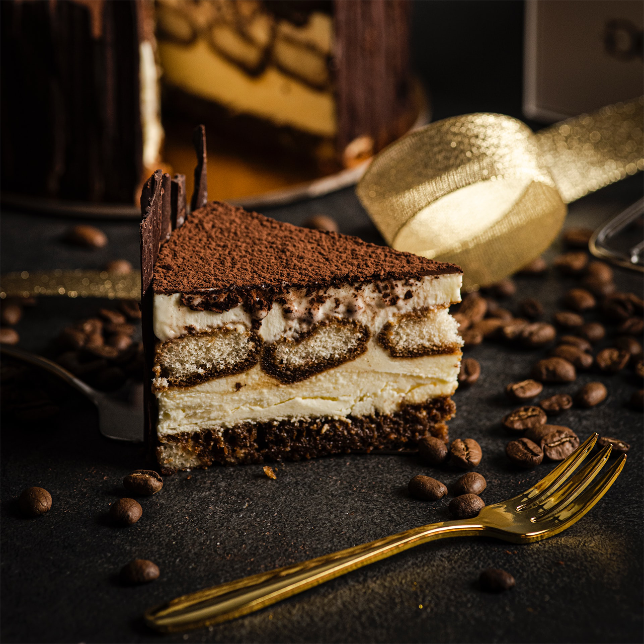 A tall tiramisu cake slice with chocolate sides and cocoa topping.