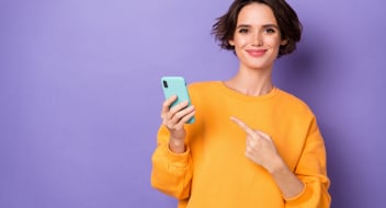 a young woman in a yellow jumper pointing at the telephone